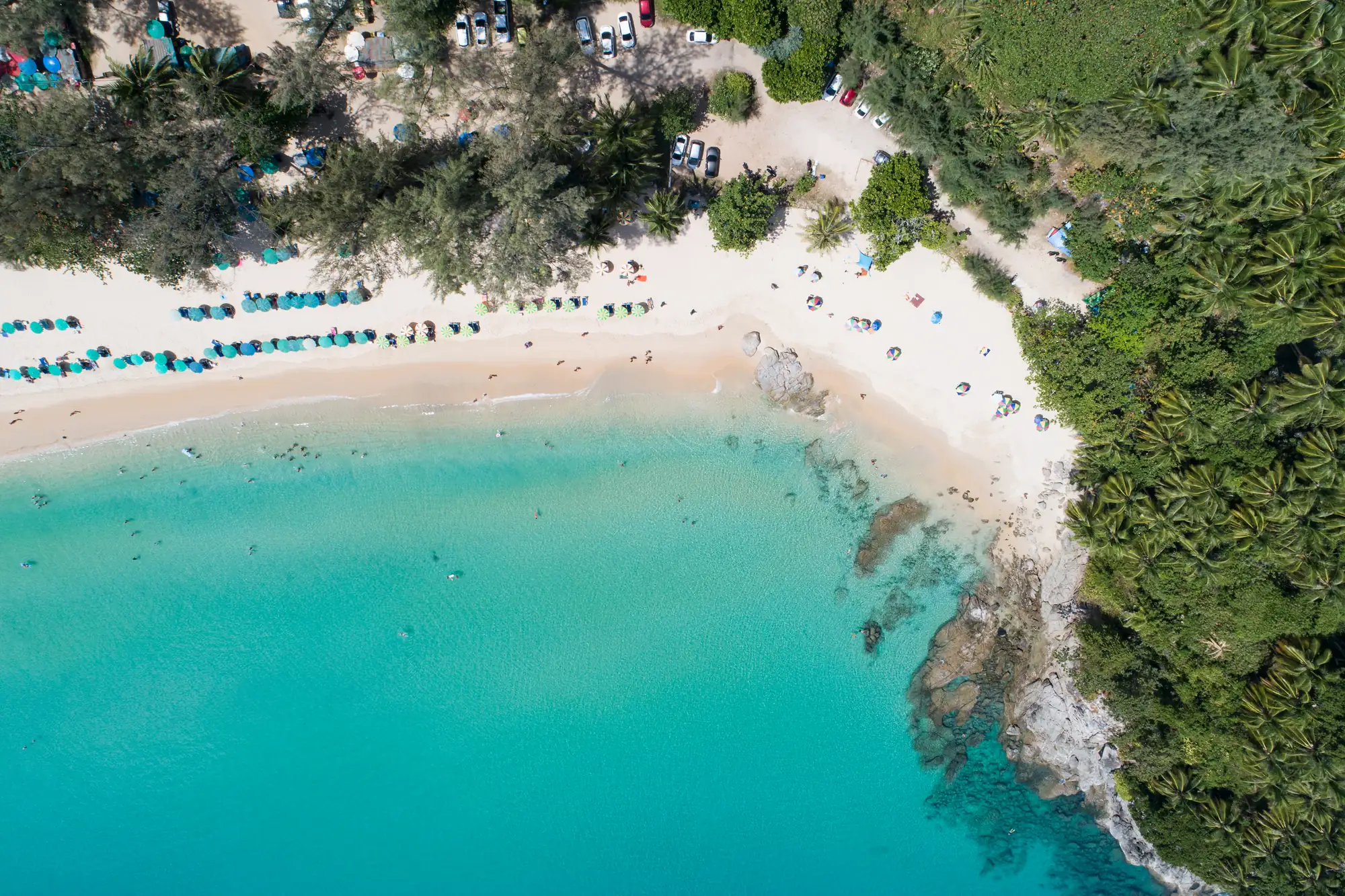 Vue aérienne de la plage de Bang Tao : sable blanc, transats et mer le long d’un rivage boisé
