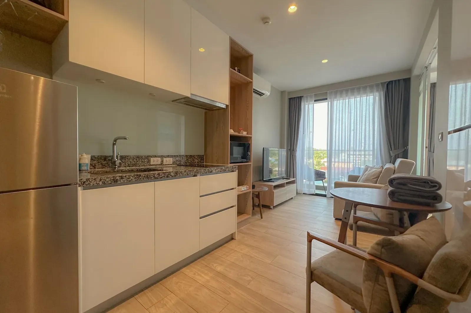 Cuisine ouverte et séjour d’un condo meublé d’une chambre, avec porte-fenêtre sur le balcon