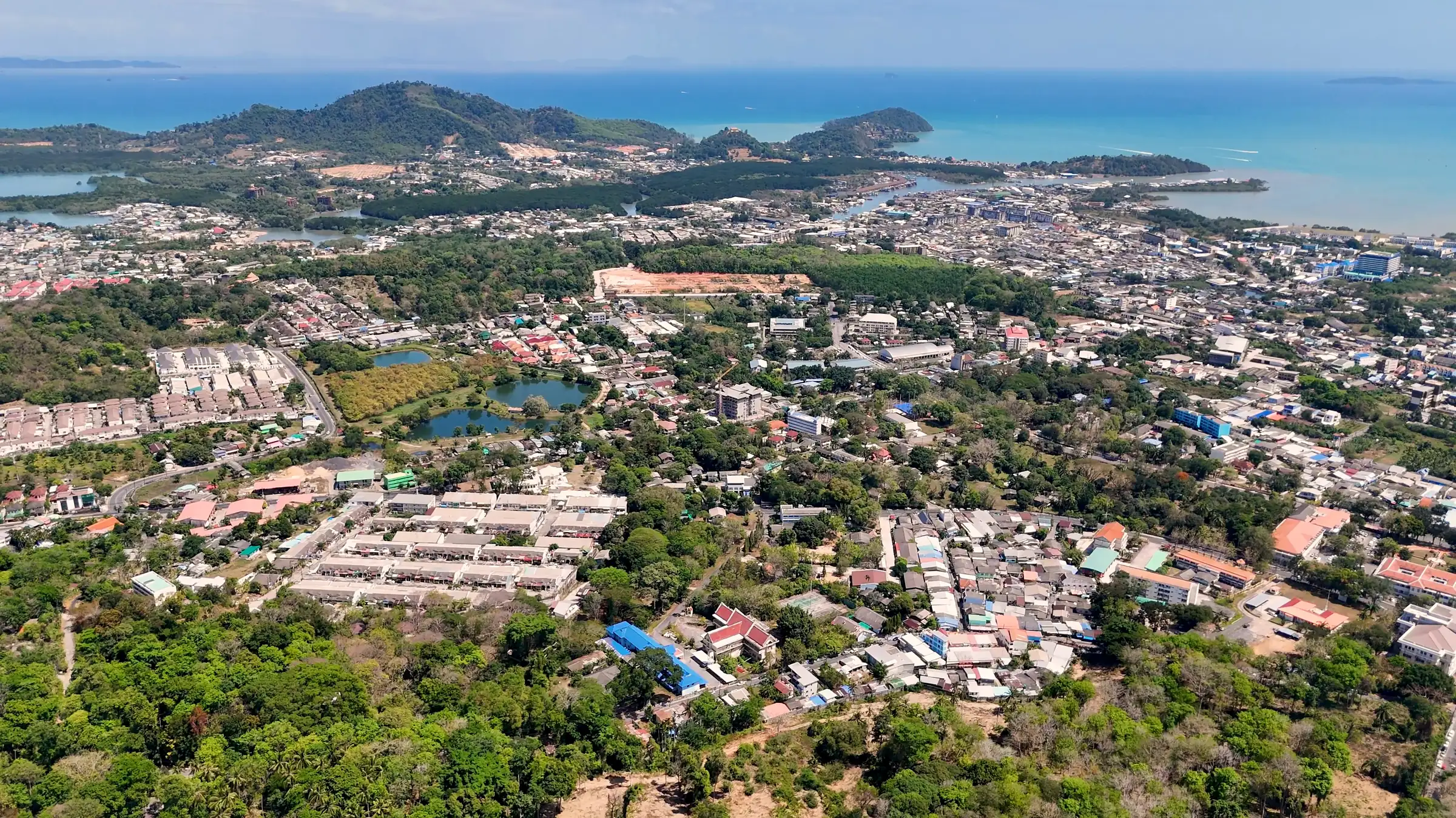 Vue aérienne de Phuket : lotissements et immeubles bas parmi les arbres, collines et mer à l’horizon