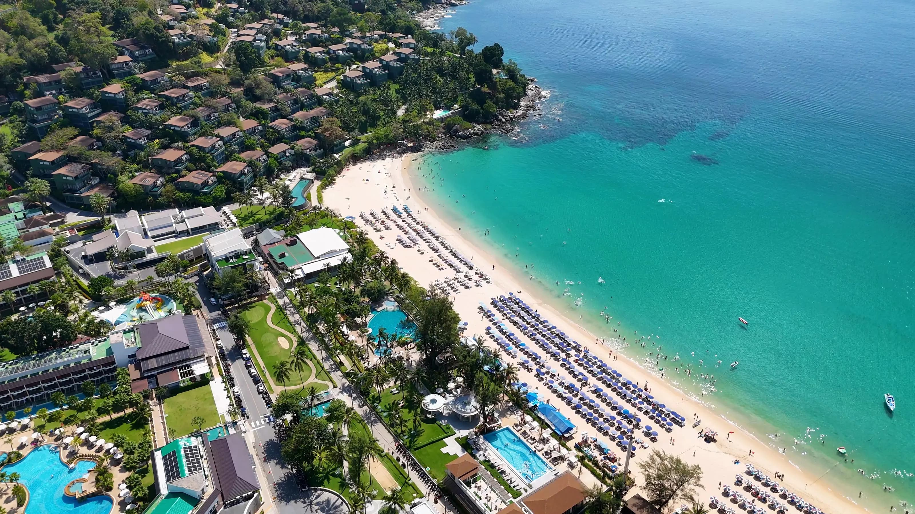 Vue aérienne d’une plage de Phuket, avec villas à flanc de colline et résidences en bord de mer